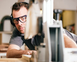 Einkommensteuer Rentensteuer - Handwerker mit Schutzbrille an einer Säge