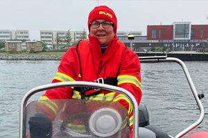 Eine Frau in roter DLRG-Bekleidung sitzt auf einem Boot im Wasser.