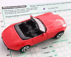 Ein Spielzeugauto auf einem Einkommensteuererklärungs-Formular
