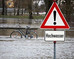 Steuererklärung: ein Schild Achtung Hochwasser steht im Wasser