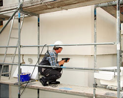 Ein Handwerker renoviert die Fassade eines Hauses