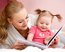 Eine Mutter liest ihrer kleinen Tochter aus einem Buch vor.