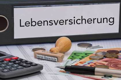 Lebensversicherung: Kapitalerträge nur zur Hälfte versteuern Schwarzer Aktenordner mit der Aufschrift „Lebensversicherung“, davor liegen Taschenrechner, Kugelschreiber und Geldscheine.