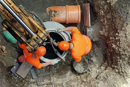 Steuerbonus für Handwerkerleistungen? Nicht bei Herstellung einer öffentlichen Mischwasserleitung! Aus der Vogelperspektive sind zwei Bauarbeiter zu sehen, die Arbeiten an Rohren unter der Erde durchführen. Dabei schauen sie in ein Rohr, das weiter nach unten führt, hinein.