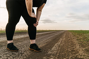 Frau in Sportkleidung hält sich das schmerzende Knie