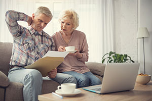 Rentner-Ehepaar blickt verwirrt auf ein Papier