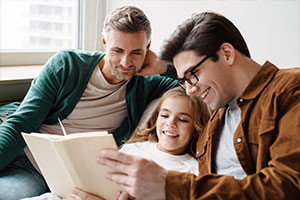 Zwei Männer lesen mit einem Mädchen