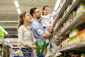 Familie mit Mutter, Vater und Kind mit Einkaufswagen im Lebensmittelgeschäft.