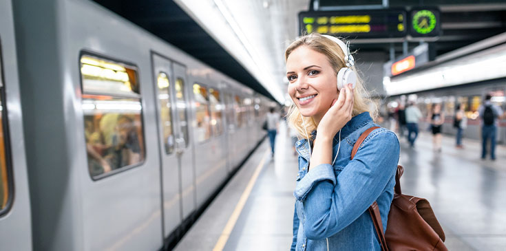 Eine fröhlich lächelnde Pendlerin wartet am Bahnsteig