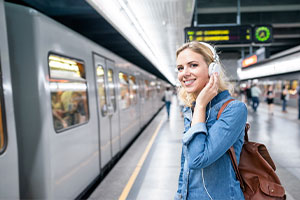 Eine fröhlich lächelnde Pendlerin wartet am Bahnsteig