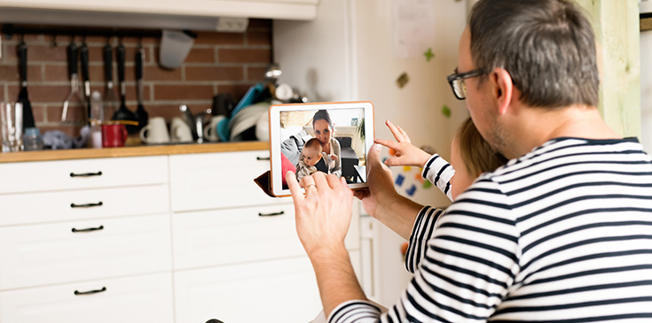 Ein Vater und sein Kind telefonieren mit der Mutter und dem Baby per Video.