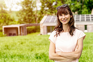 Eine junge Frau steht im Garten vor einer Photovoltaikanlage