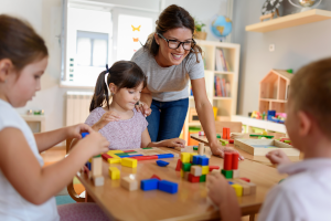 Kindergärtnerin mit Kindern, die mit buntem Holzspielzeug im Kindergarten spielen