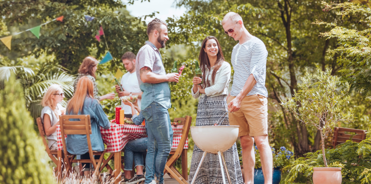Sommerfest im Betrieb: Müssen Arbeitnehmer den geldwerten Vorteil versteuern? Eine Gruppe junger Menschen feiert ein Sommerfest. Sie grillen auf einer Wiese.