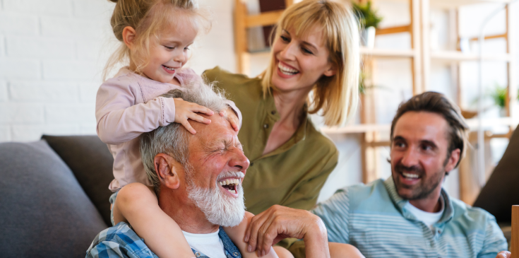 Steuern 2025: Was ändert sich für Arbeitnehmer? Eine Familie sitzt im Wohnzimmer zusammen und lacht.