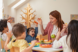 Fröhliche Erzieherin betreut Kinder in einer Kindertagesstätte – Kinderbetreuungskosten steuerlich absetzen mit Tipps vom Steuerring.