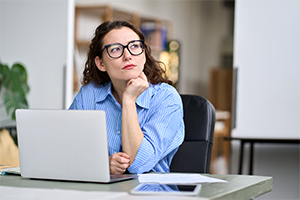 Nachdenkliche Frau mit Brille am Laptop – sie fragt sich, was das Finanzamt über sie weiß. Der Steuerring hilft bei Fragen rund um das Thema.