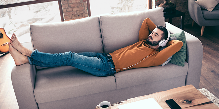Ein Mann liegt entspannt mit einem Laptop auf dem Sofa – sichtbar erleichtert, weil er dank des Steuerrings von der Möglichkeit einer Fristverlängerung wusste. 
