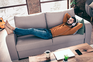 Ein Mann liegt entspannt mit einem Laptop auf dem Sofa – sichtbar erleichtert, weil er dank des Steuerrings von der Möglichkeit einer Fristverlängerung wusste. 