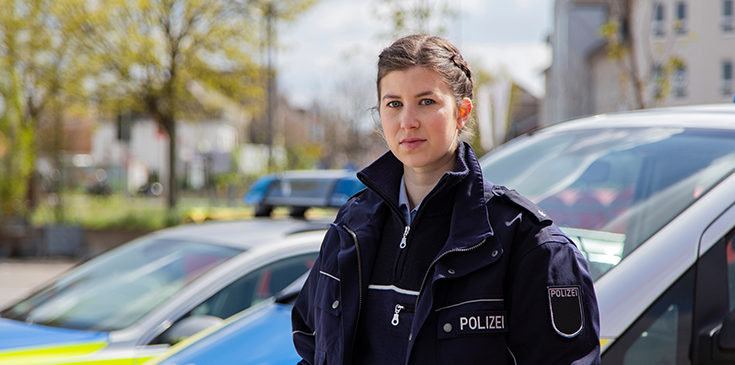 Steuertipps für Polizisten: Das können Beamte bei der Steuer absetzen Eine junge Polizistin steht vor einem Auto. Dank der Unterstützung durch das Unternehmen Steuerring kennt sie ihre steuerlichen Vorteile.