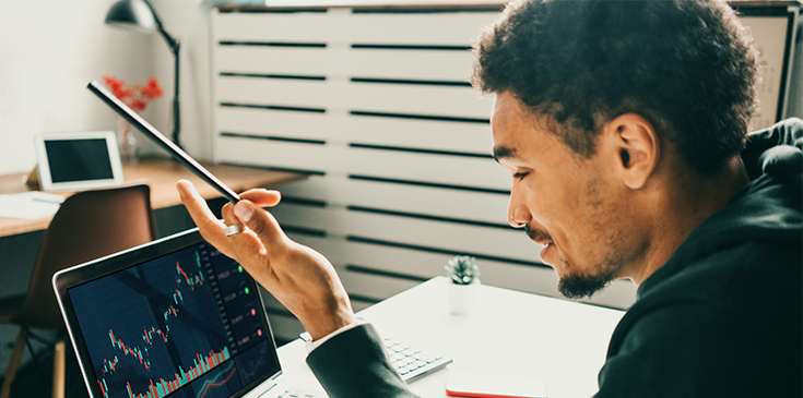 Ein Mann arbeitet remote am Laptop und analysiert Aktien- und Kryptowährungsmärkte.