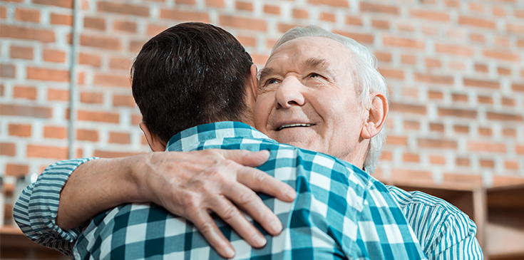 Eine herzliche Umarmung zwischen einer älteren und einer jüngeren Person. Der Beitrag erklärt das Pflegegeld.