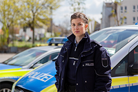 Steuertipps für Polizisten: Das können Beamte bei der Steuer absetzen Eine junge Polizistin steht vor einem Auto. Dank der Unterstützung durch das Unternehmen Steuerring kennt sie ihre steuerlichen Vorteile.