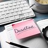 Ein aufgeschlagener Kalender mit Post It auf dem das Wort „Deadline“ steht