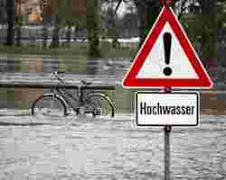 Steuererklärung: ein Schild Achtung Hochwasser steht im Wasser