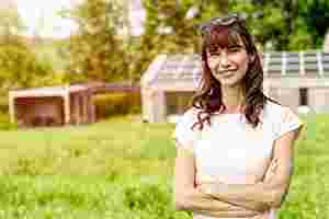 Eine junge Frau steht im Garten vor einer Photovoltaikanlage