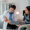 Ein Arzt untersucht den Fuß einer Patientin in einer modernen Arztpraxis.