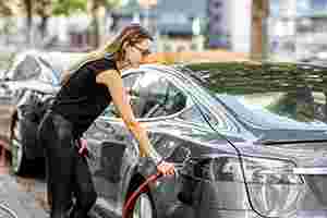Eine junge Frau lädt ihr Elektrofahrzeug auf.