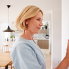 Nahaufnahme einer Frau, die zu Hause am Thermostat die Temperatur der Zentralheizung einstellt.