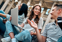 Drei Studierende diskutieren über Steuertipps vom Steuerring, während eine Person einen Laptop in der Hand hält.