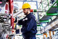 Ein Monteur im Blaumann arbeitet in einer Industrieanlage.