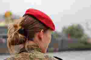 Eine junge Soldatin von hinten mit einem roten Barett auf dem Kopf.