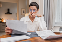 Eine Frau sitzt grübelnd über der Steuererklärung eines verstorbenen Familienmitgliedes - der Steuerring kann helfen.