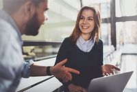 Welche Steuern und Abgaben muss ein Werkstudent zahlen? Junge Frau, am Laptop sitzend, erklärt ihr Projekt.