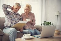 Das lang erwartete Bundesfinanzhof-Urteil zur Doppelbesteuerung der Renten ist da – was nun? Rentner-Ehepaar blickt verwirrt auf ein Papier