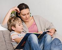 Alleinerziehende und der Entlastungsbetrag: BFH-Urteil zum Familiensplitting Mutter und Kind sitzen auf dem Sofa und lesen bzw. lernen in einem Buch.
