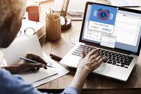 Abgabefrist der Einkommensteuererklärung 2018: neue Regeln für Pflichtveranlagte Eine Frau sitzt vor einem Laptop und bearbeitet ihren digitalen Kalender. Auf dem Bildschirm ist eine Erinnerung in Form eines Weckerbildes aufgeploppt. In der linken Hand hält die Frau einen Bleistift, auf dem Schreibtisch liegen im Hintergrund eine Brille, Unterlagen und weitere Stifte.