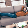 Ein Mann liegt entspannt mit einem Laptop auf dem Sofa – sichtbar erleichtert, weil er dank des Steuerrings von der Möglichkeit einer Fristverlängerung wusste. 