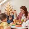 Fröhliche Erzieherin betreut Kinder in einer Kindertagesstätte – Kinderbetreuungskosten steuerlich absetzen mit Tipps vom Steuerring.