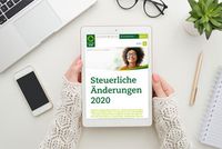 Steuern 2020: Was ändert sich? Zwei Frauenhände halten ein Tablet. Auf dessen Bildschirm ist die Steuerring-Website und die Aufschrift „Steuerliche Änderungen 2020“ zu erkennen. Um das Tablet herum liegen auf einem Schreibtisch eine Brille, ein Handy, ein Block mit Stift, eine Pflanze und ein Laptop.