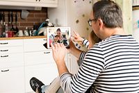 Ein Vater und sein Kind telefonieren mit der Mutter und dem Baby per Video.